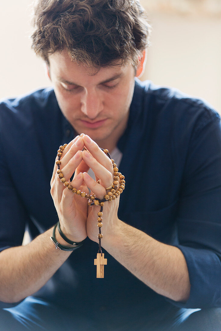 Serene man praying with rosary