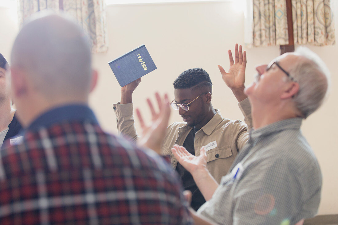 Men with bible praying with arms raised