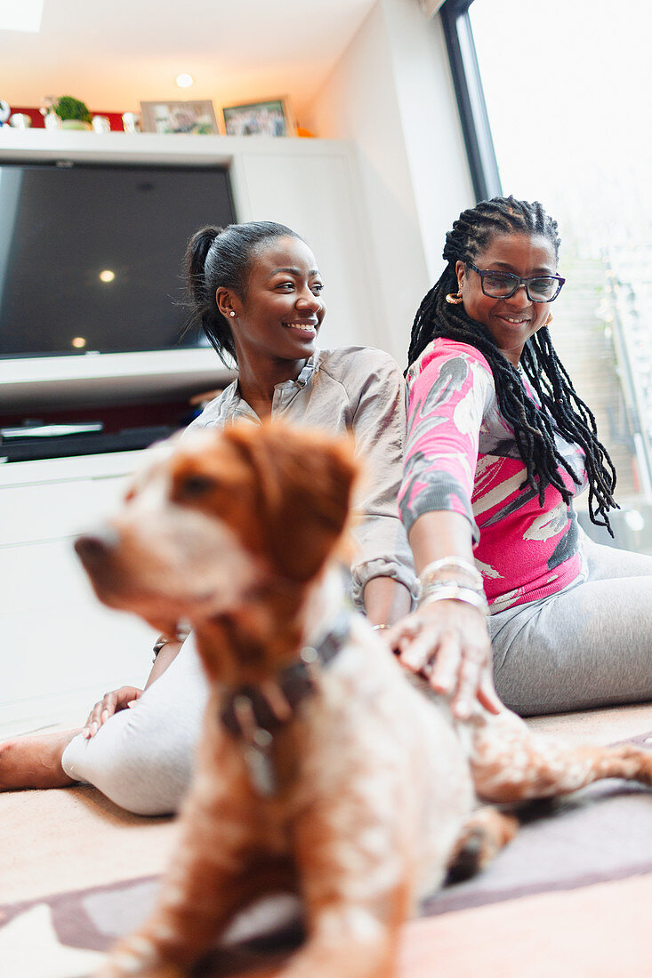 Mother and adult daughter with dog on living room floor