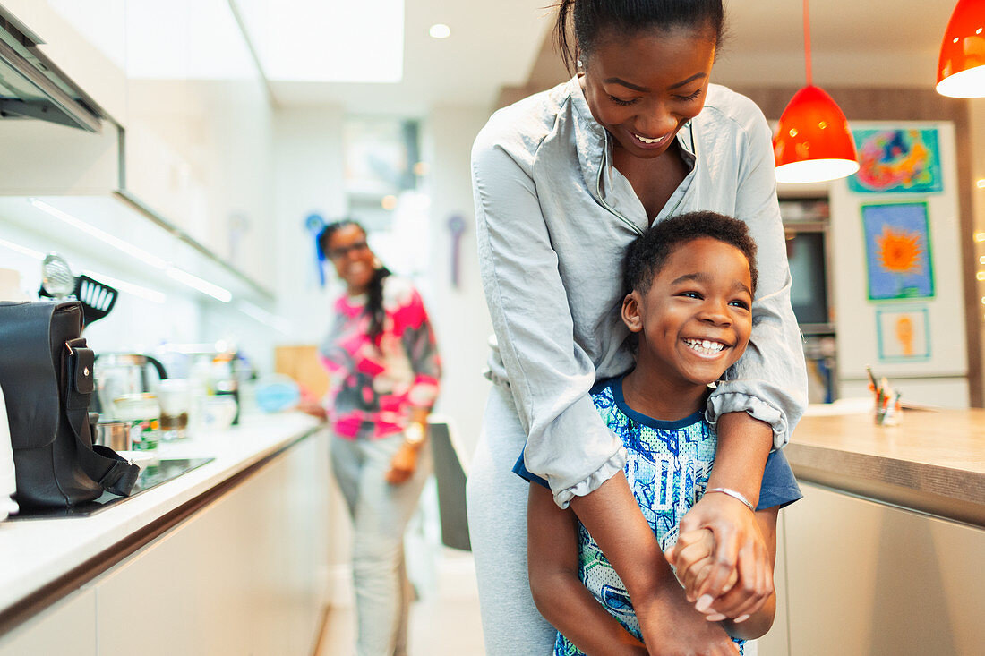 Affectionate mother and son hugging in kitchen