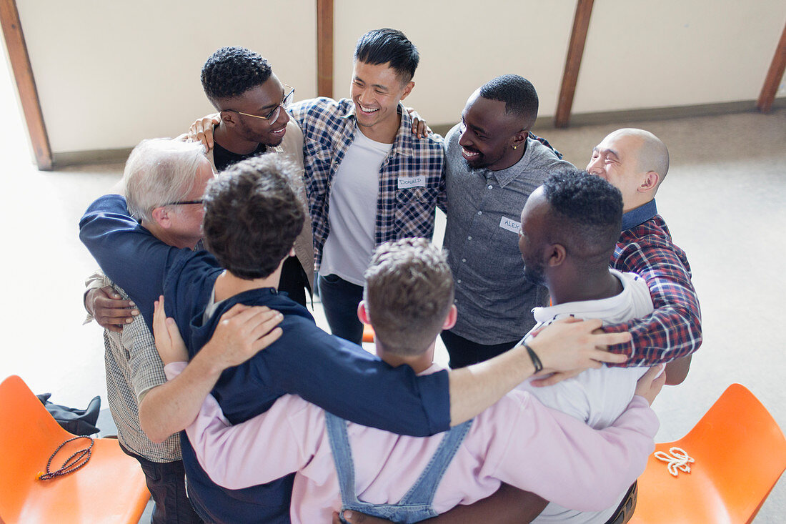 Men hugging in circle in group therapy