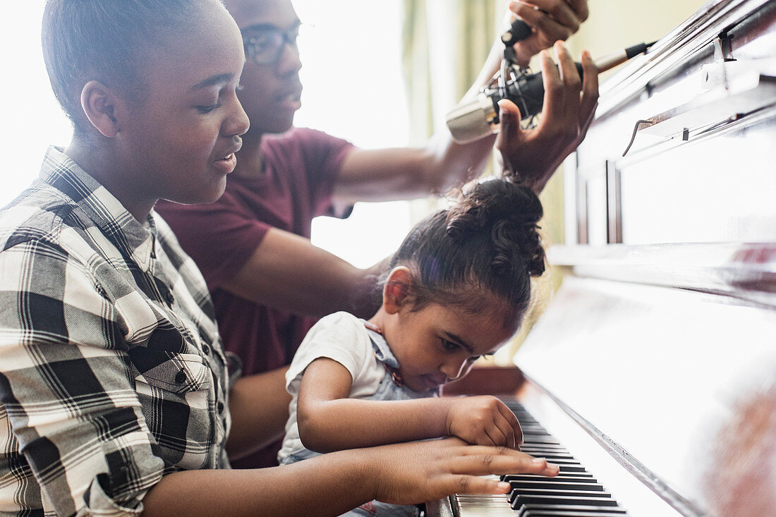 Brother and sisters playing piano