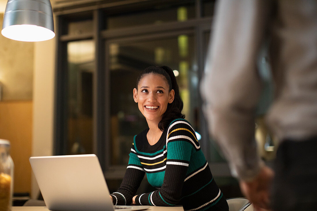 Smiling woman using laptop at home at night