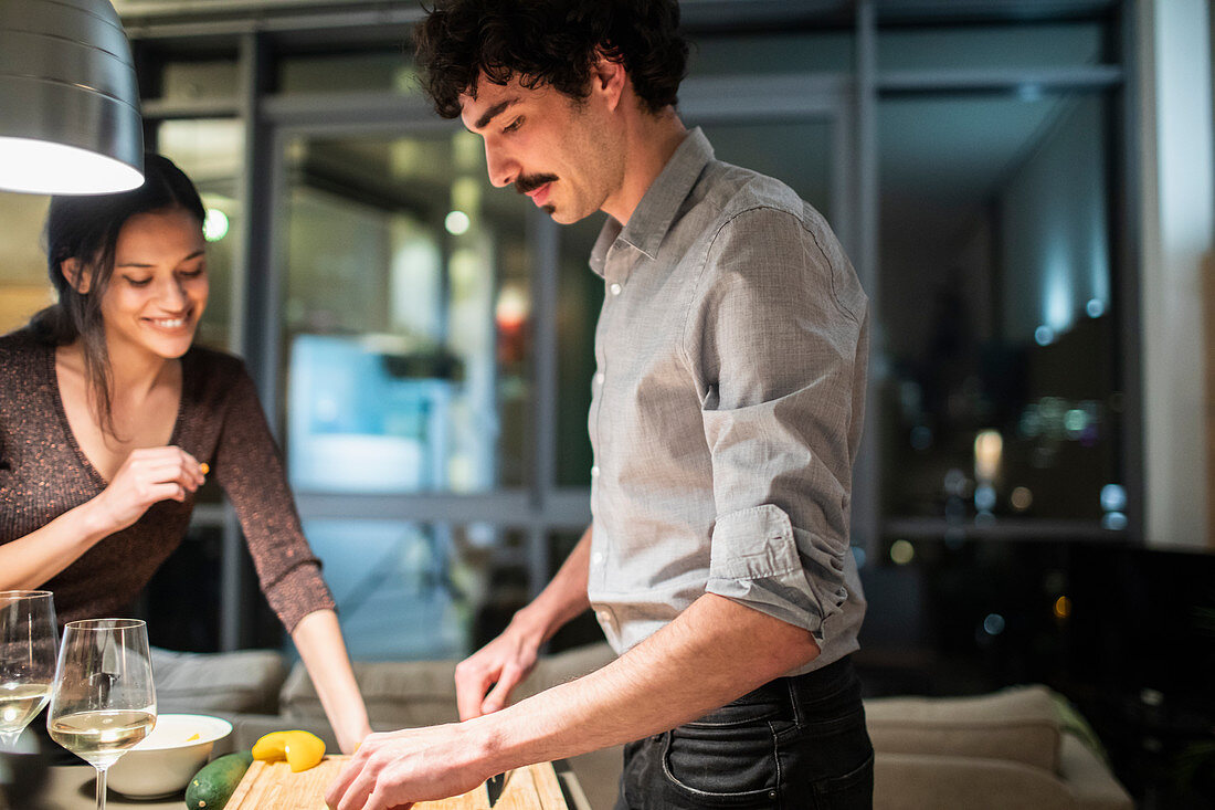 Couple cooking dinner in apartment kitchen at night
