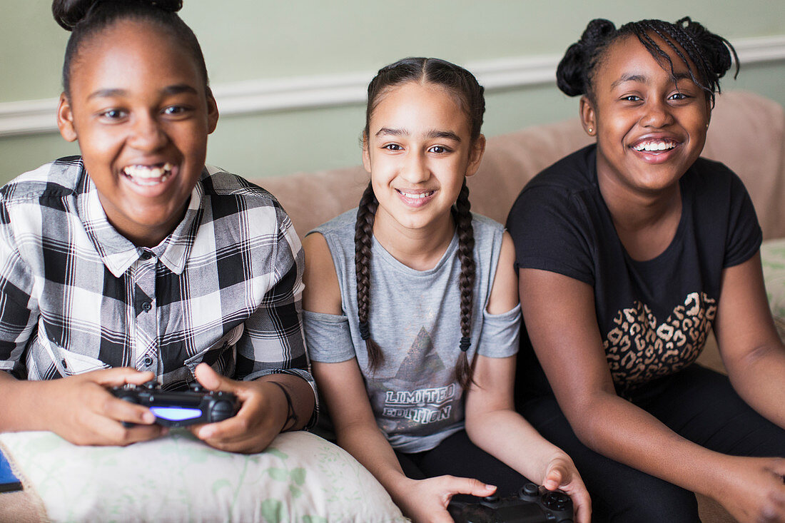 Portrait smiling tween girl friends playing video game