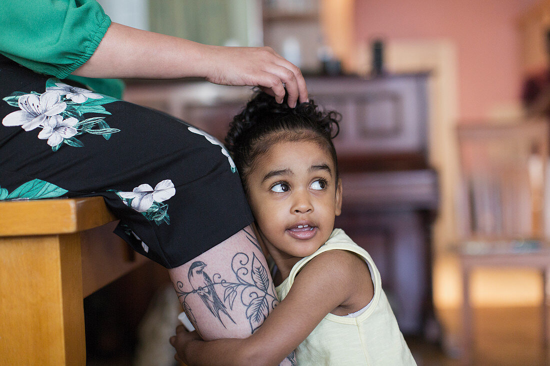 Cute toddler girl hugging mothers legs