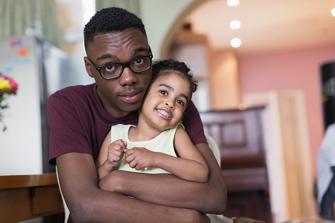 Teenage brother hugging toddler sister