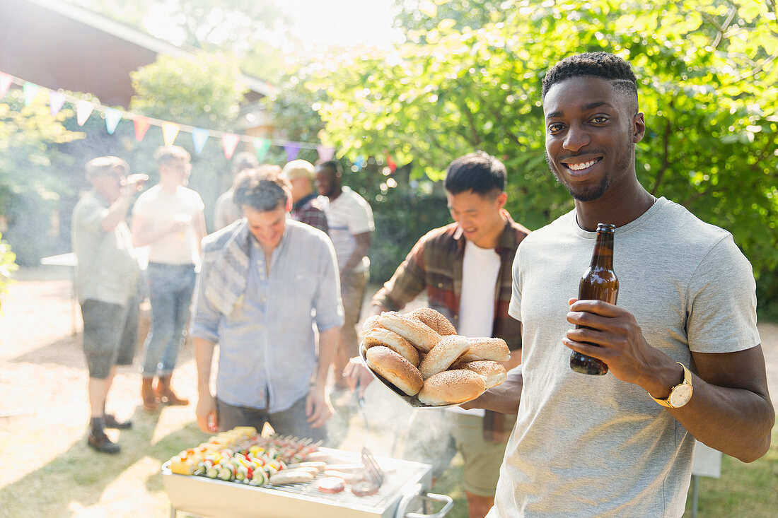 Portrait man drinking beer, enjoying barbecue in backyard