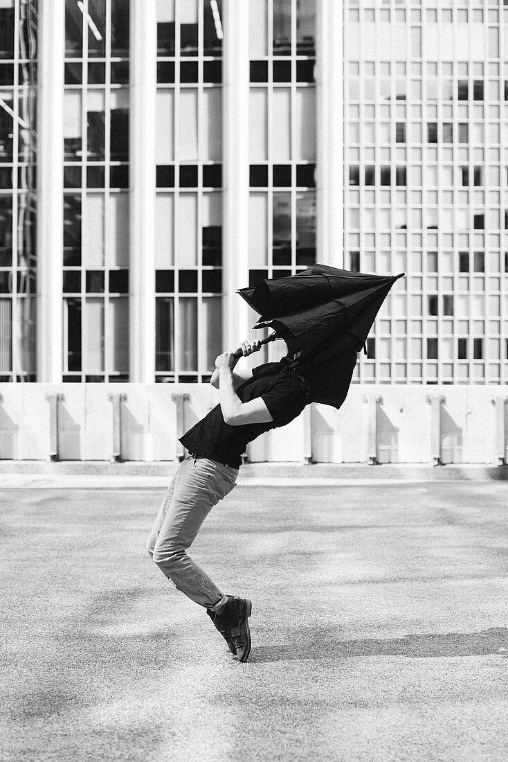 Man dancing with umbrella covering head