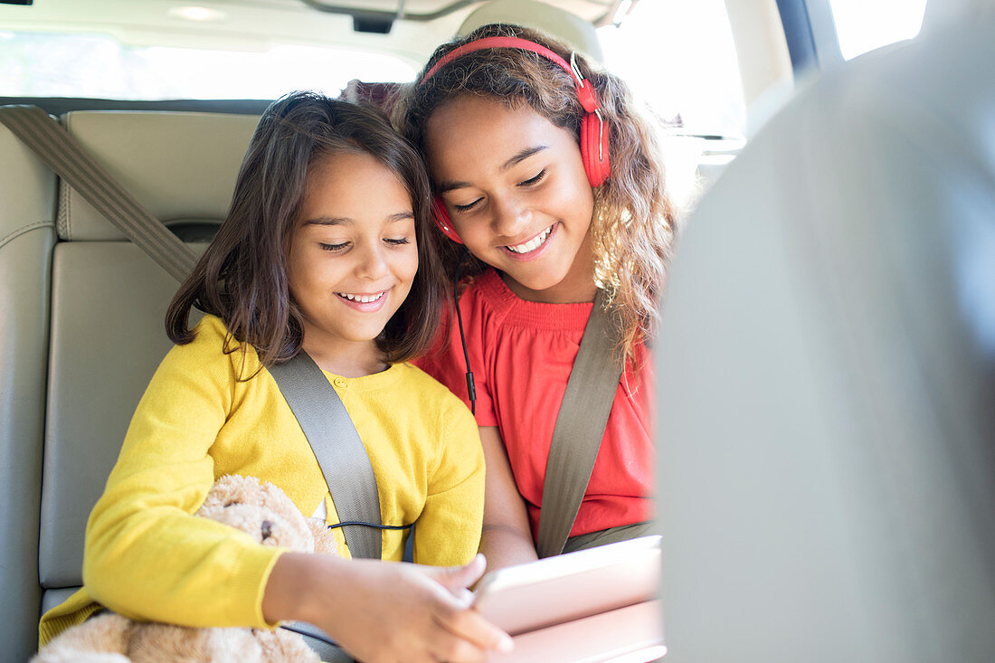 Sisters using tablet in back set of car