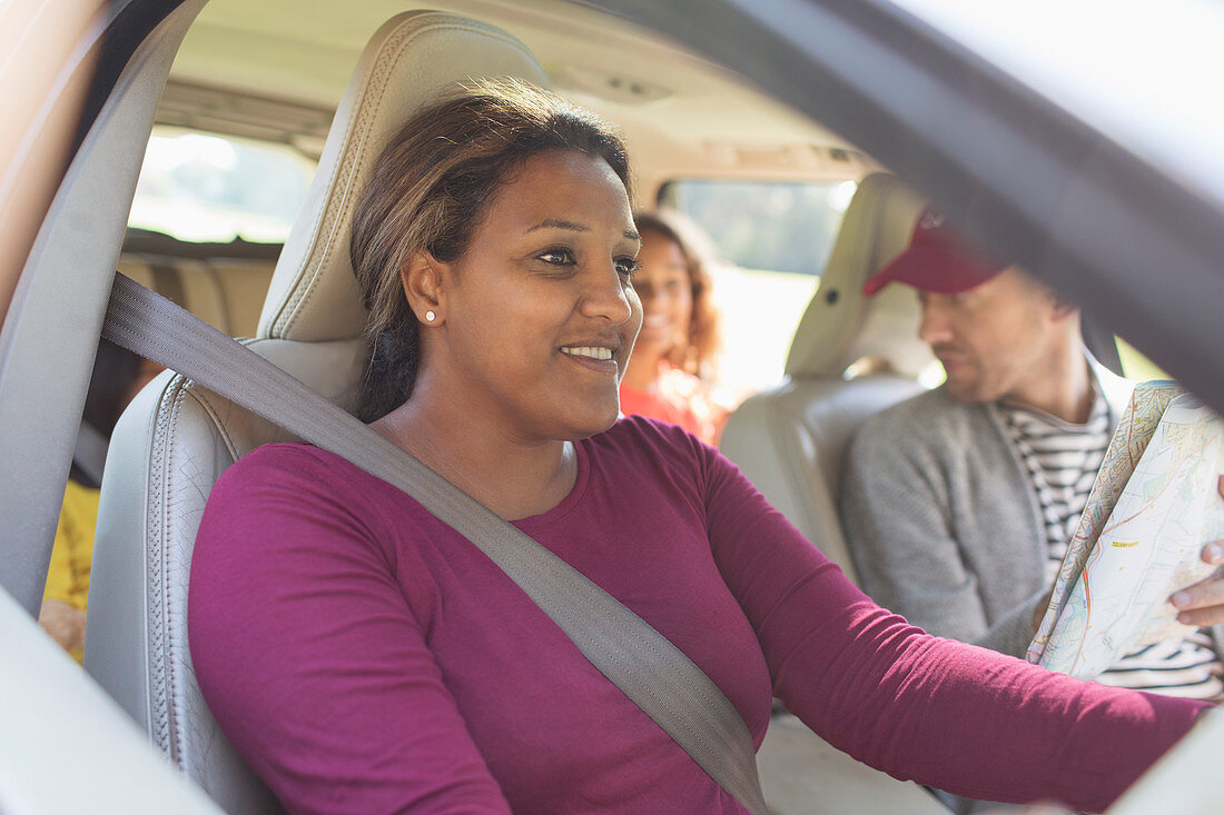 Smiling woman driving car with family on road trip