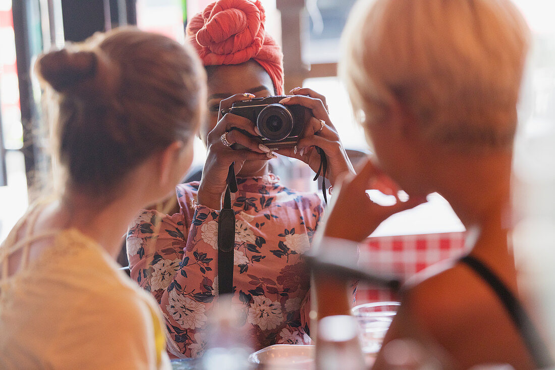 Young woman photographing friends with camera