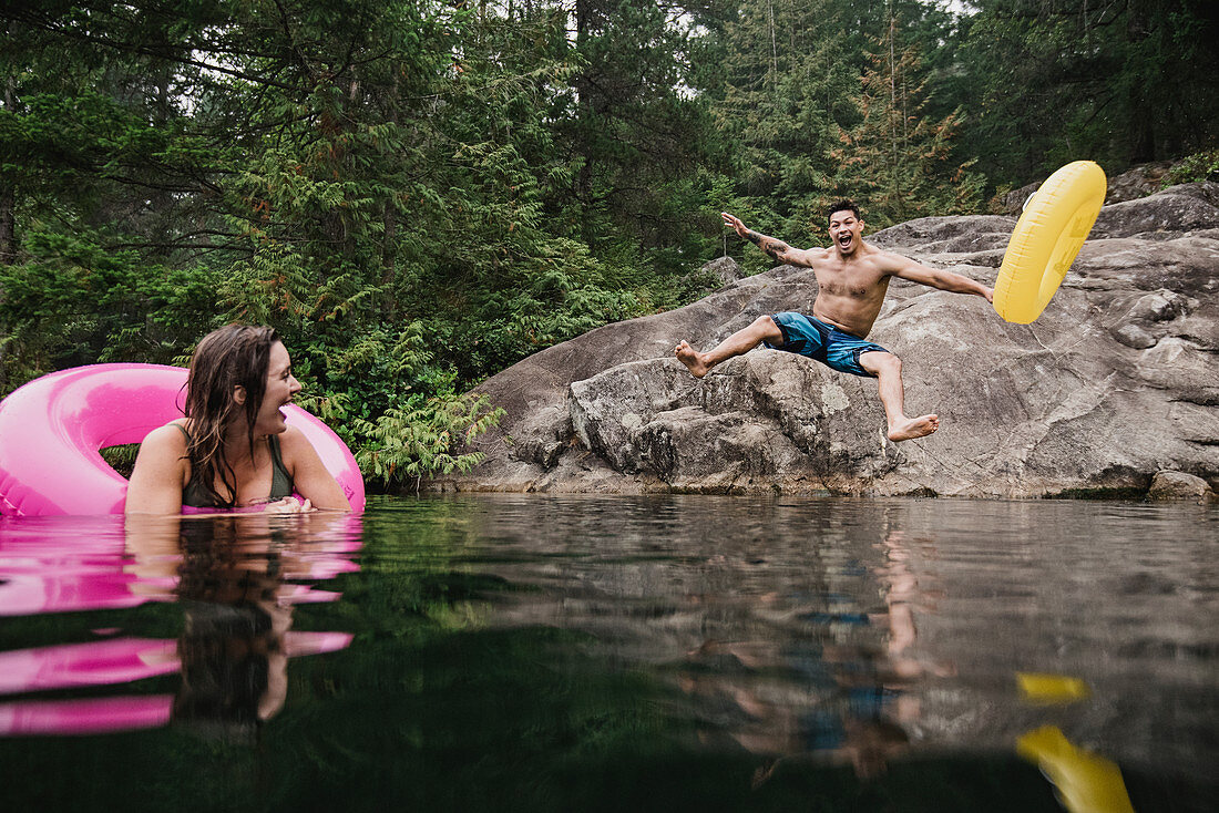 Playful man jumping into lake, Canada