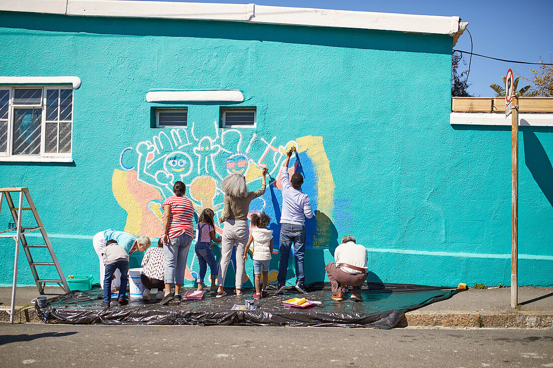 Community volunteers painting vibrant mural on urban wall