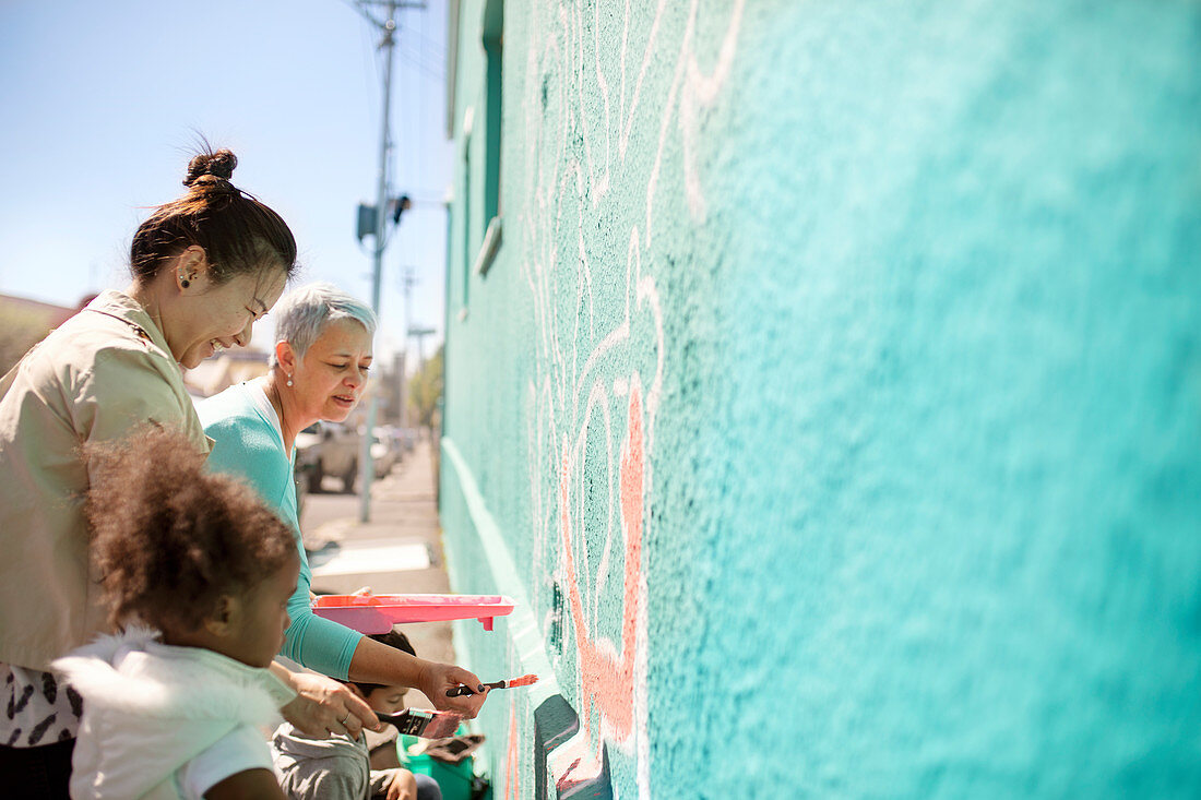 Female volunteers painting mural on wall