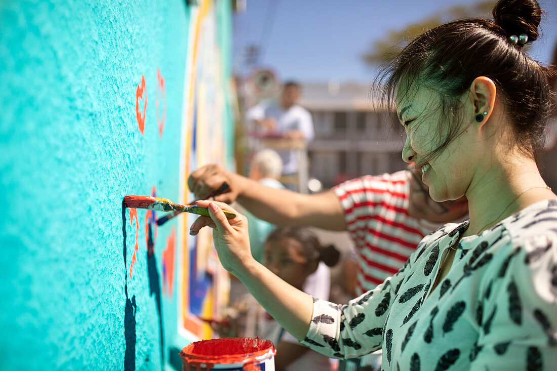 Smiling volunteer painting mural on wall