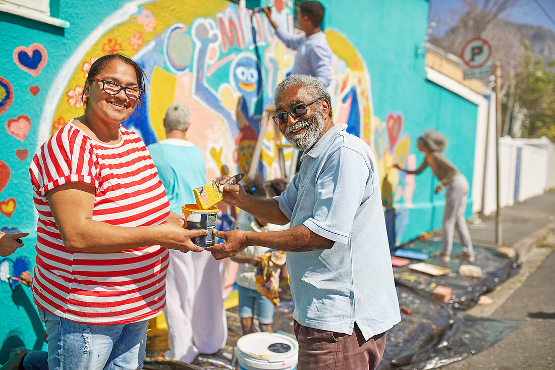 Portrait community volunteers painting mural on urban wall