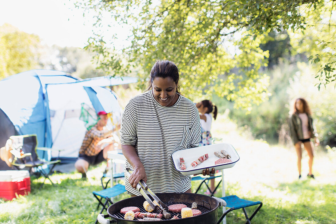 Smiling woman barbecuing lunch for family