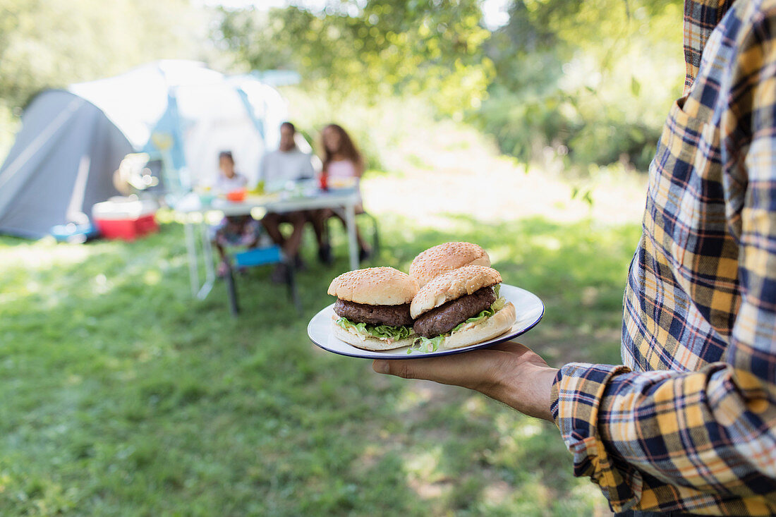 Father serving barbecue hamburgers to family