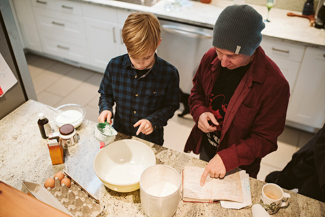 Father and son baking, looking at recipe