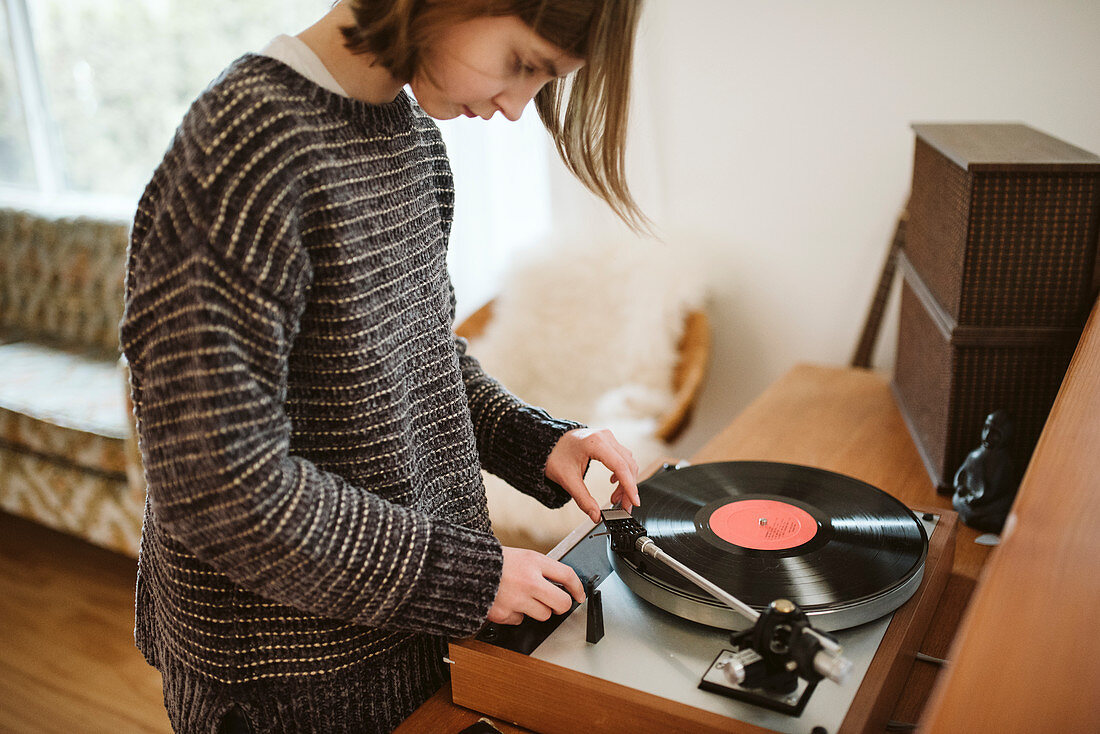 Girl playing vinyl record in living room