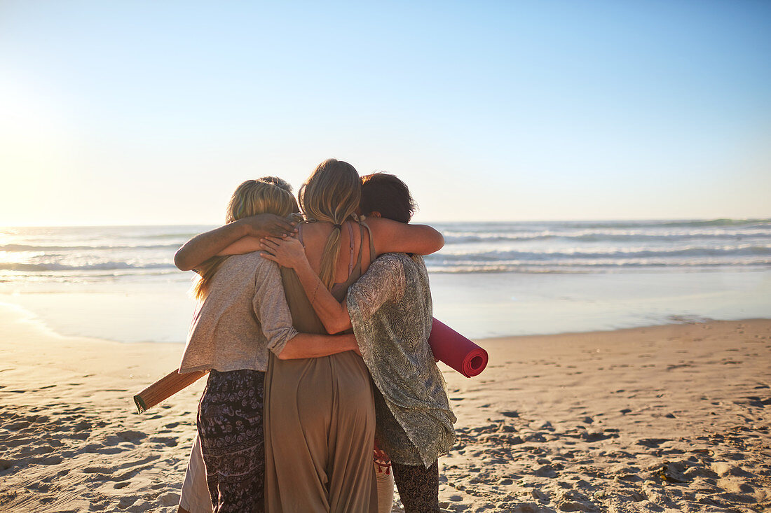 Female friends with yoga mats hugging