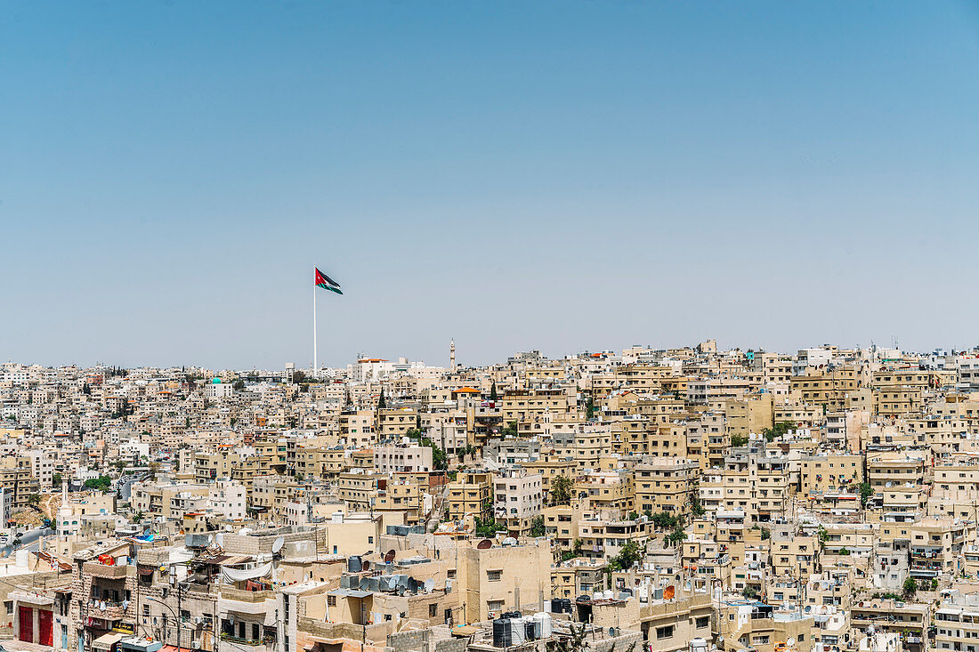 Jordanian flag flying over city buildings, Jordan