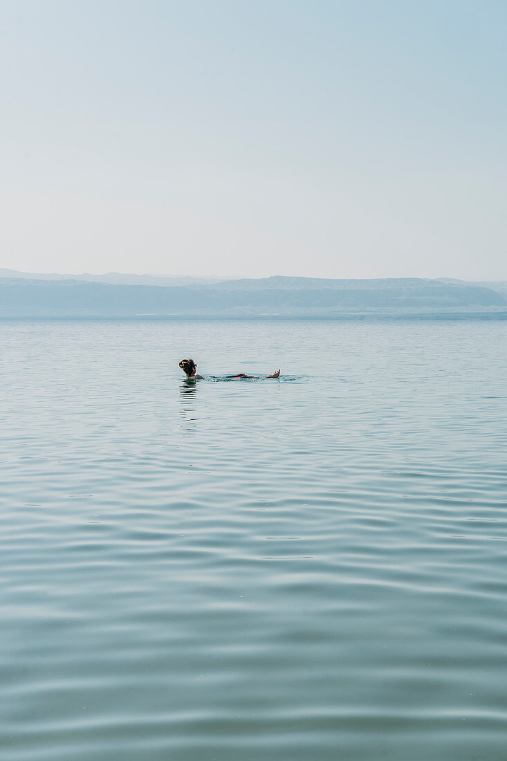 Man floating, swimming in Dead Sea, Jordan