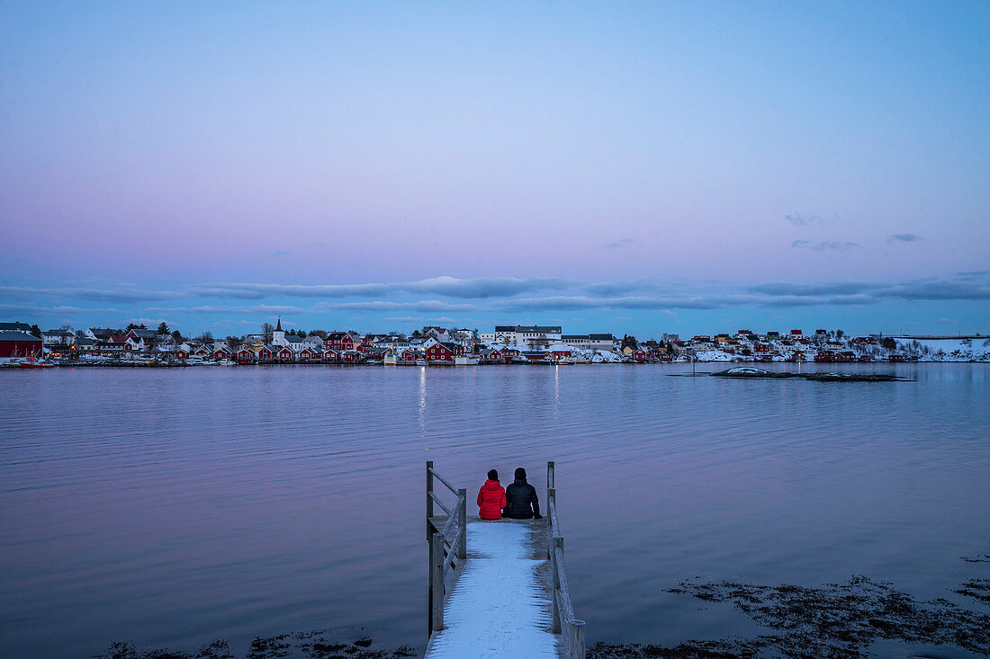 Couple sitting at the edge of snowy pier, Norway