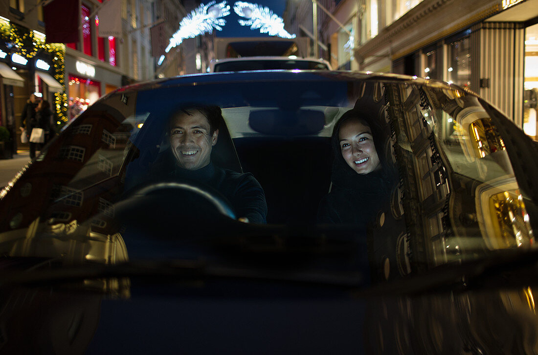 Smiling couple driving car at night