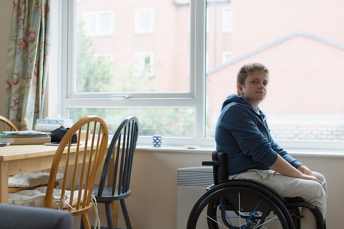 Portrait woman sitting in wheelchair at window