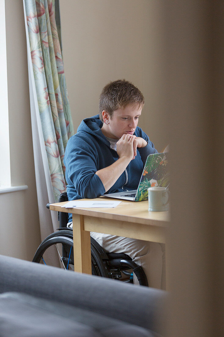 Focused woman in wheelchair using laptop