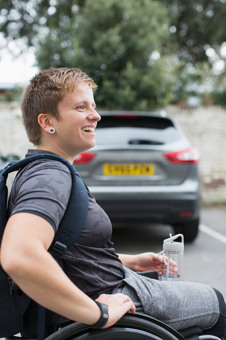 Young university student in wheelchair in parking lot