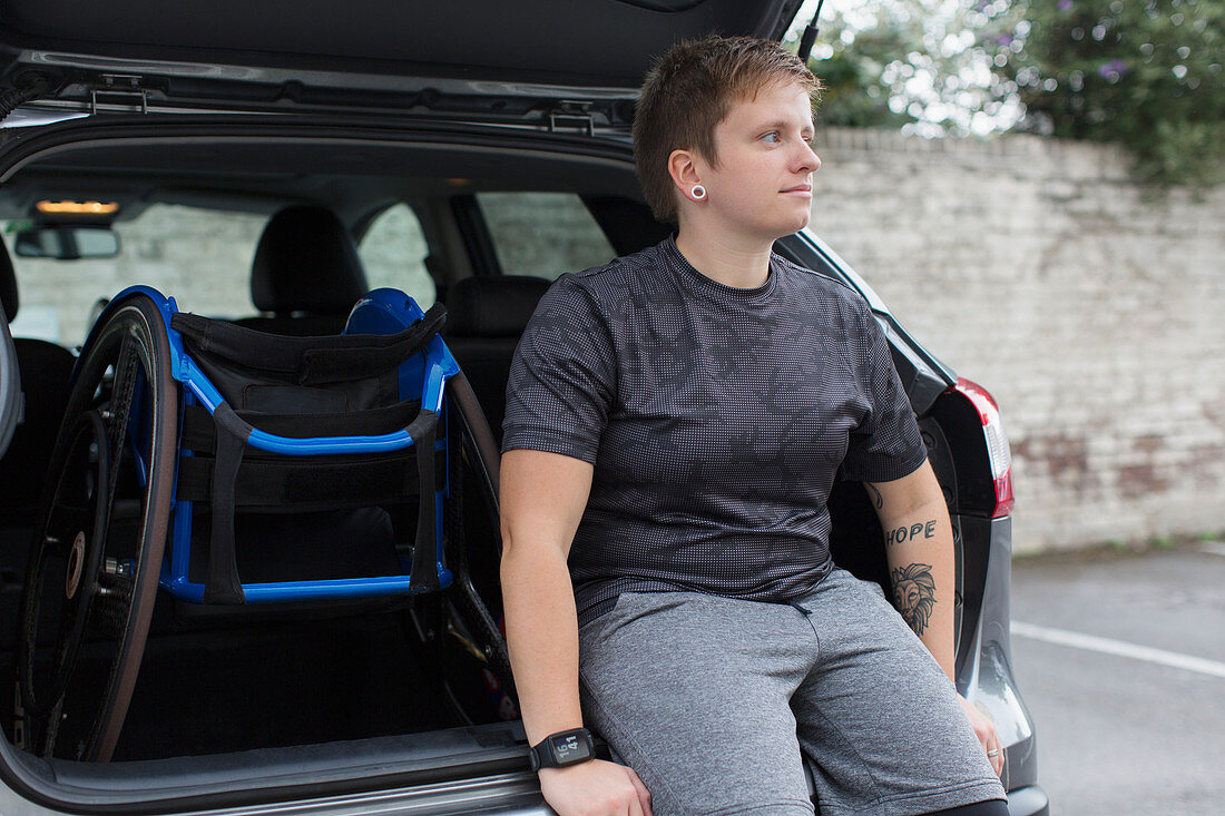 Confident woman with wheelchair at back of car