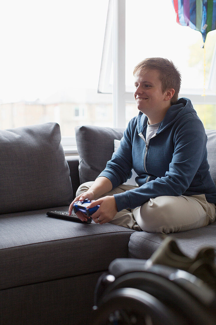 Smiling woman playing video game on sofa
