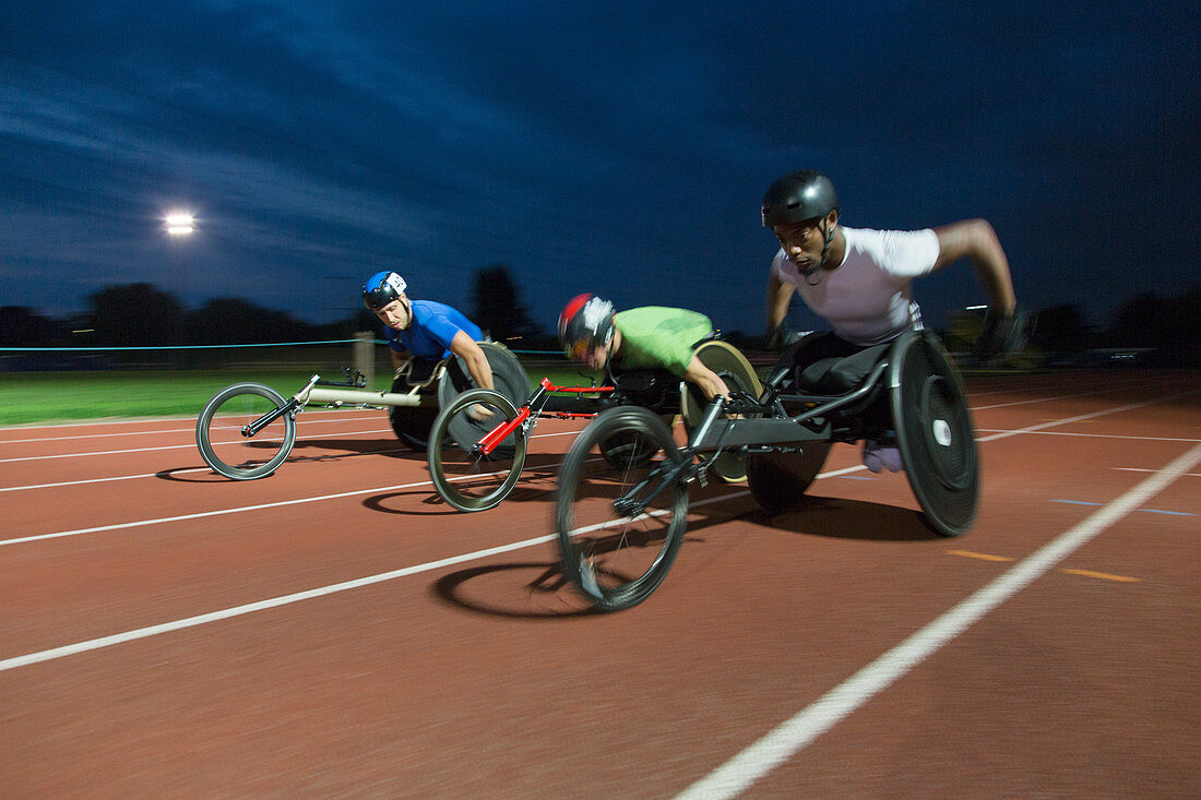 Paraplegic athletes racing along sports track in night