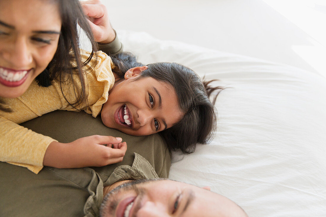 Portrait parents and daughter cuddling on bed