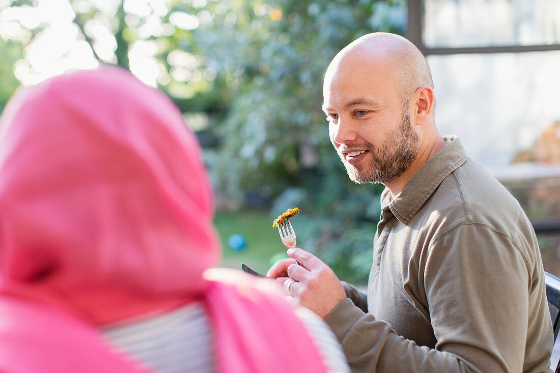 Man eating with wife in hijab