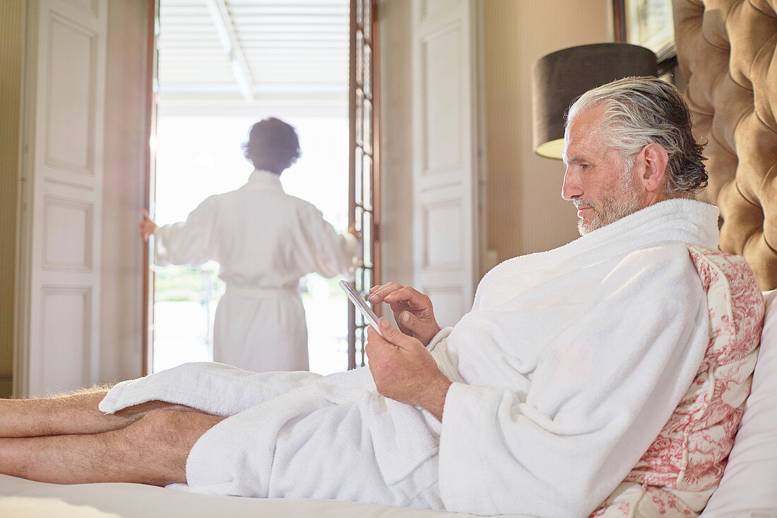Mature man using digital tablet on hotel bed