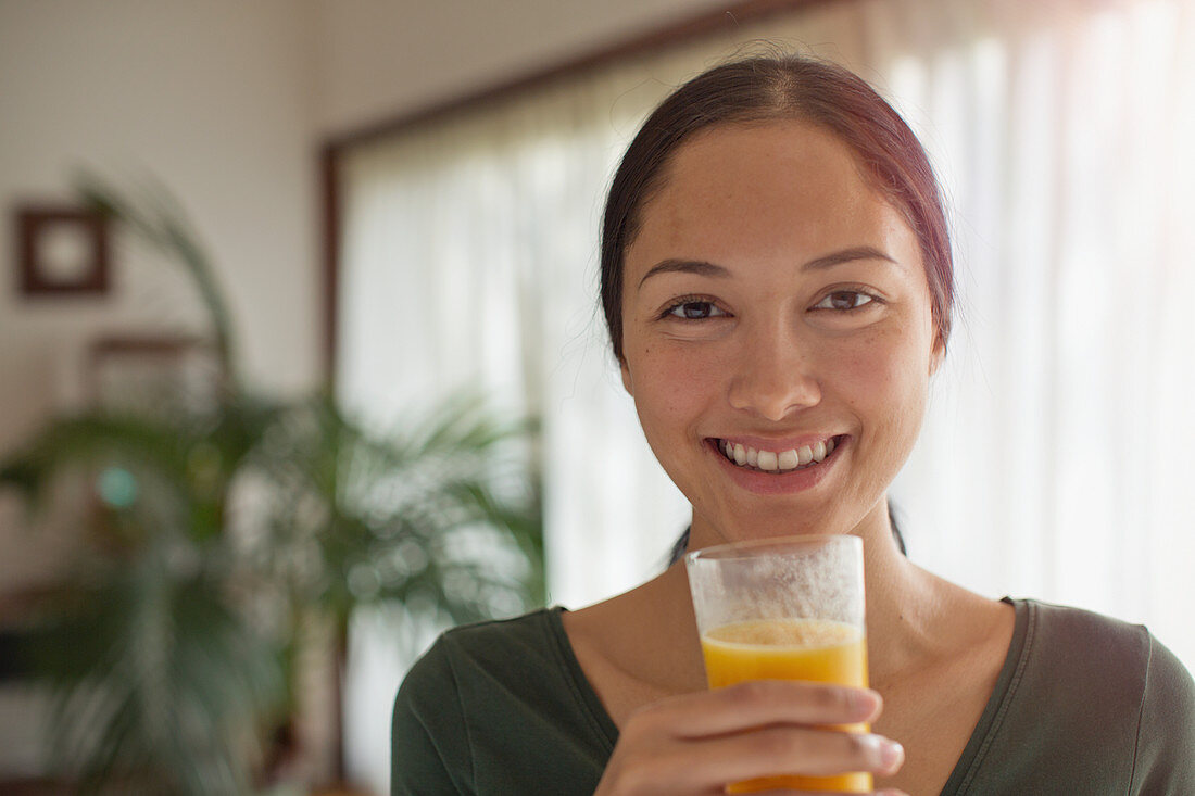 Portrait confident young woman drinking orange juice