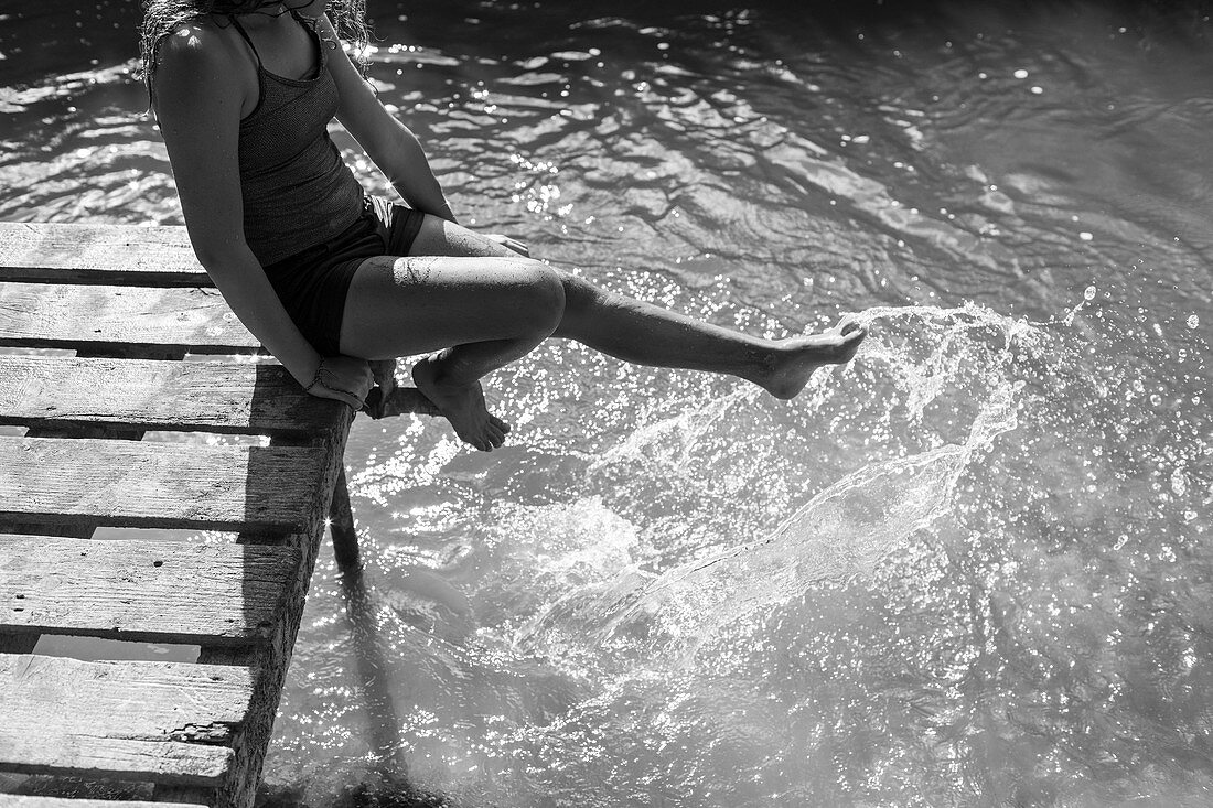 Playful girl splashing feet in river