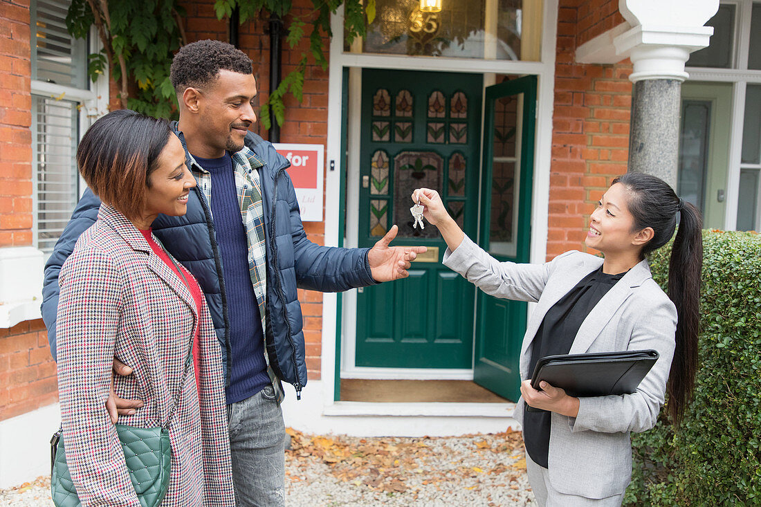 Real estate agent giving house keys to couple