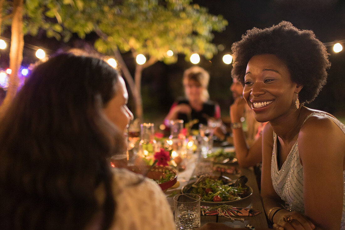 Happy women friends enjoying dinner garden party