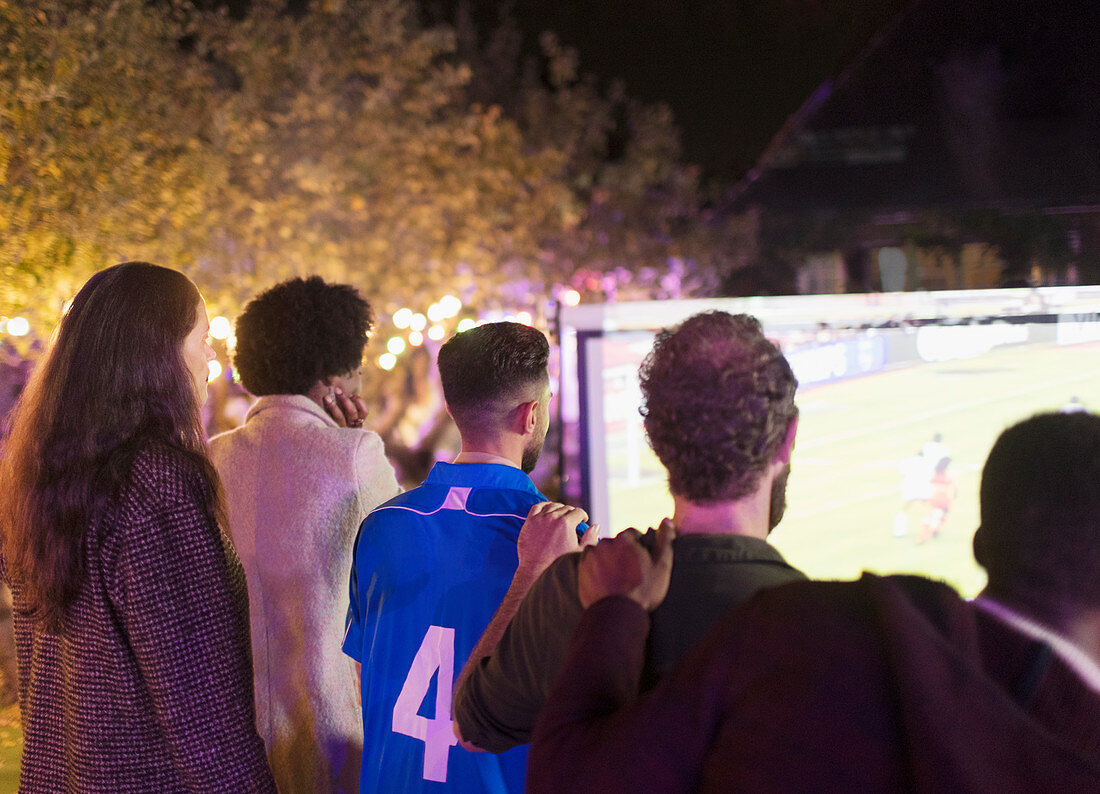 Friends watching soccer match on screen