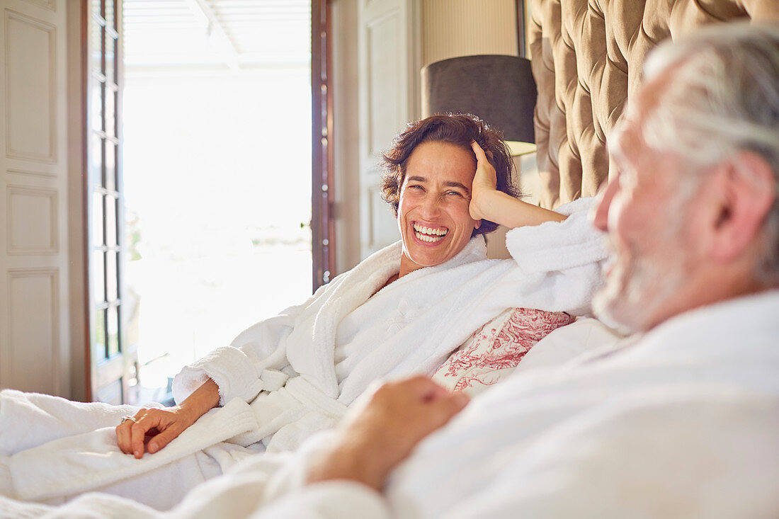 Happy, laughing mature couple relaxing on hotel bed