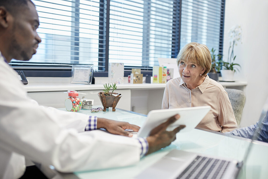 Doctor with digital tablet talking to senior patient