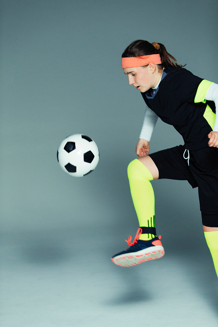 Teenage girl soccer player kicking the ball