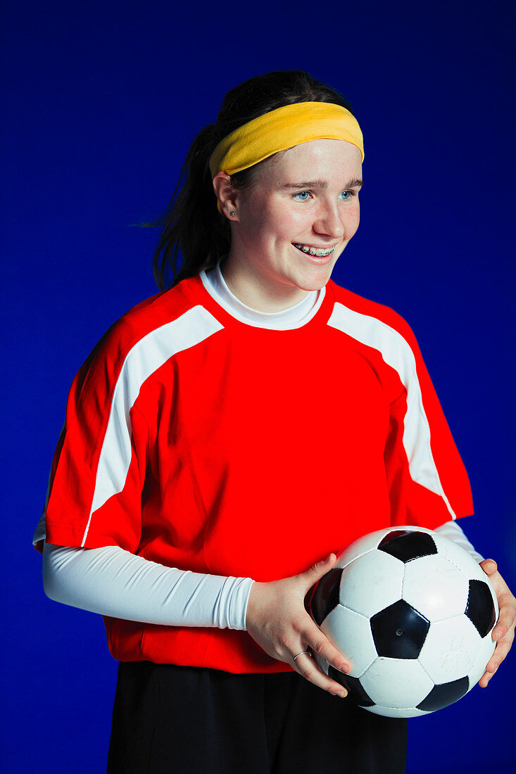 Teenage girl soccer player holding ball