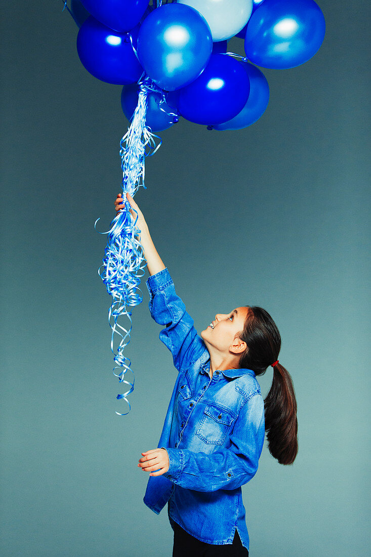 Tween girl holding blue balloon bunch