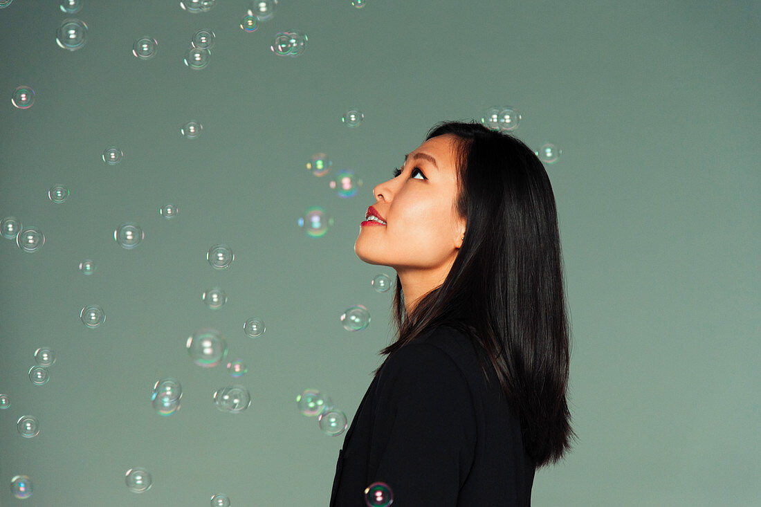 Young woman watching falling bubbles